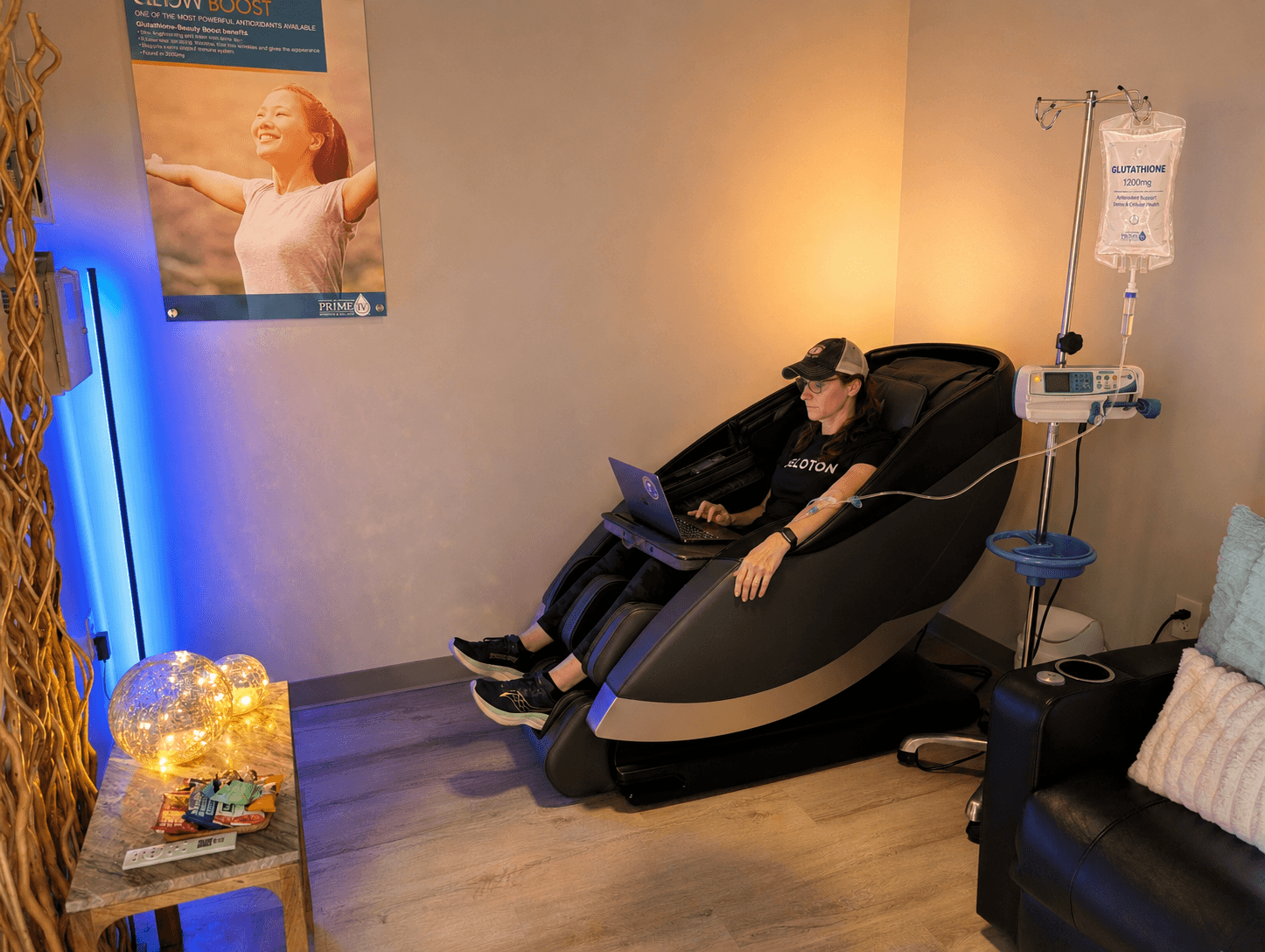 A client working on her laptop from a zero-gravity massage chair while receiving a Glutathione IV drip at Prime IV Hydration & Wellness in Huntsville, AL