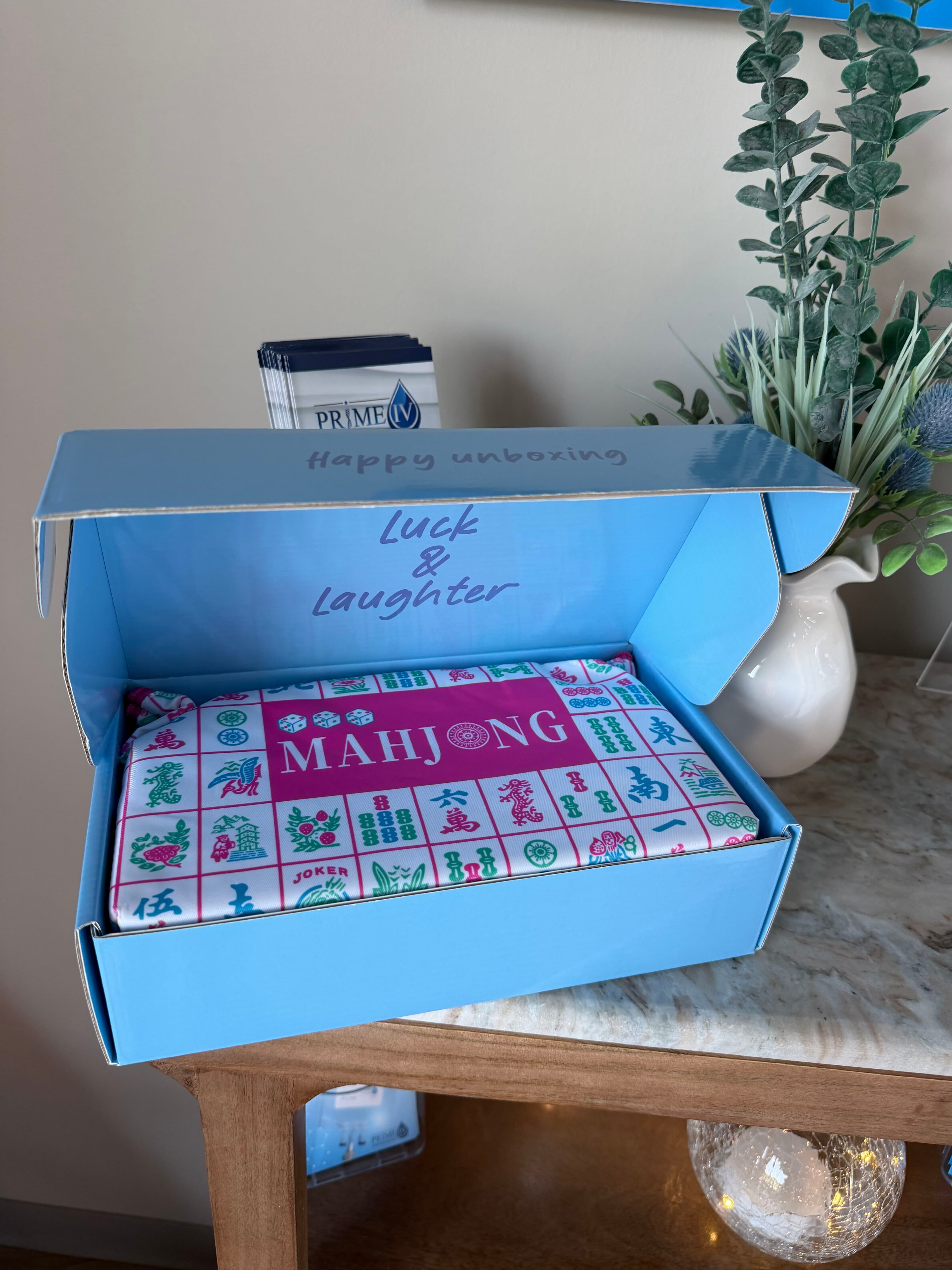 The Luck & Laughter mahjong set — a pink and white 'MAHJONG' zip case in a Prime IV gift box — the raffle prize for Mahjong Night